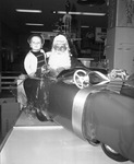 Close-up of Santa Claus holding small boy in front of gift wrapped toy car in a toy department, Arlington, Texas