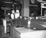 Santa Claus holding small boy in front of gift wrapped toy car in a toy department, Arlington, Texas