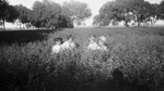 A family in a field of flowers by Basil Clemons 1887-1964