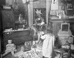 Child in cluttered room by Basil Clemons 1887-1964