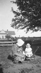 Child in a baby stroller with an adult by Basil Clemons 1887-1964