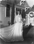 Unidentified bride wearing her wedding dress in a yard beside a house by Basil Clemons 1887-1964