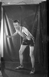 A man posing in a basketball players uniform by Basil Clemons 1887-1964