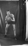 A man in a basketball players uniform posing with a basketball by Basil Clemons 1887-1964