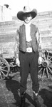 A cowboy standing in front of a wooden wagon by Basil Clemons 1887-1964