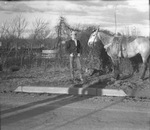 A young man standing next to a saddled horse by Basil Clemons 1887-1964