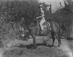 A cowgirl posing with her horse by Basil Clemons 1887-1964