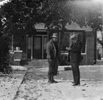 Two men standing in front of a brick house after a snowfall by Basil Clemons 1887-1964