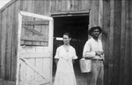 A couple outside a barn by Basil Clemons 1887-1964