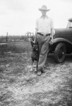 A man and his dog next to a car by Basil Clemons 1887-1964