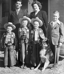 A young couple with four young boys pose in front of a house by Basil Clemons 1887-1964