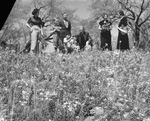 A group of people standing in a field of bluebonnets by Basil Clemons 1887-1964