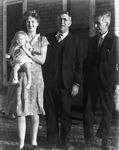 Two men, a woman, and a child posing in front of a house by Basil Clemons 1887-1964