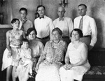 An extended family, all dressed in white or very light-colored clothing, posing around a sofa by Basil Clemons 1887-1964