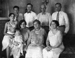 An extended family, all dressed in white or very light-colored clothing, posing around a sofa by Basil Clemons 1887-1964