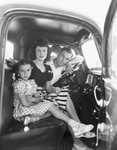 A young couple and a young girl sitting in a truck by Basil Clemons 1887-1964