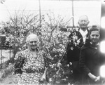 An elderly couple and a young woman pose next to a small flowering tree by Basil Clemons 1887-1964