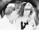 A young couple sitting in an automobile with a baby by Basil Clemons 1887-1964