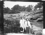 A couple standing near a stream by Basil Clemons 1887-1964