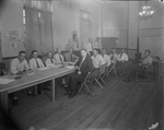 A group of men, possibly associated with the Red Cross, are seated at a long table by Basil Clemons 1887-1964