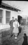 A couple stand in front of a house by Basil Clemons 1887-1964