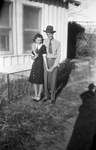 A couple stand in front of a house by Basil Clemons 1887-1964