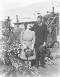 A couple standing in front of flowers by Basil Clemons 1887-1964