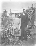 A couple stands in front of some flowers by Basil Clemons 1887-1964