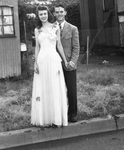 A couple standing in front of a house by Basil Clemons 1887-1964