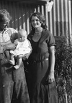 A father holds a baby with his wife stands next to him by Basil Clemons 1887-1964