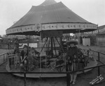 Children on a small carousel at a circus by Basil Clemons 1887-1964