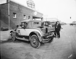 Two men in business suits look over a new car/truck with a wooden cargo bed outside a Buick dealership, Breckenridge, Texas. by Basil Clemons 1887-1964