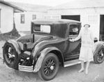 Woman wearing a cloche hat stands next to shiny new auto truck with a wooden cargo bed, Breckenridge, Texas by Basil Clemons 1887-1964