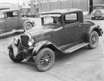 A damaged car with front and rear windshields broken out, parked on a city street, Breckenridge, Texas by Basil Clemons 1887-1964