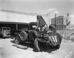 A wrecked pick-up truck parked outside a garage by Basil Clemons 1887-1964