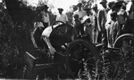 Several men and boys stand around a race car that has crashed in the trees by Basil Clemons 1887-1964