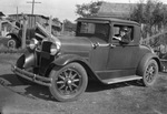 Man sits in driver's seat of a roadster car, Breckenridge, Texas by Basil Clemons 1887-1964