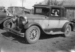 Man sits in driver's seat of a roadster car by Basil Clemons 1887-1964