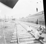 The John Robinson's Circus train arriving at a train station, with several African American men sitting on railroad tracks by Basil Clemons 1887-1964