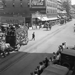 Crowds lined along a wide street, watching a circus parade by Basil Clemons 1887-1964