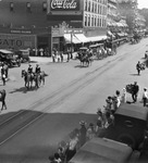 Crowds lined along a street, watching a circus parade by Basil Clemons 1887-1964