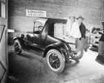 Two men sit in the wooden cargo bed of a vehicle at a Lincoln dealer, Breckenridge, Texas by Basil Clemons 1887-1964