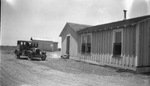 Four-door car is parked outside a small house in the country by Basil Clemons 1887-1964