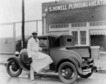 African-American man stands beside a truck parked in front of S. Howell Plumbing & Heating, Breckenridge, Texas by Basil Clemons 1887-1964