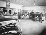 Chevrolet automobile dealership showroom with salesmen standing near cars by Basil Clemons 1887-1964