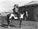 Man dressed in Native American costume astride a paint horse by Basil Clemons 1887-1964