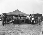 John Robinson's Circus; circus workers stand near small tent that shelters crates and boxes, Breckenridge, Texas by Basil Clemons 1887-1964