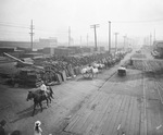 Teams of horses and men move beside large stacks of lumber next to the railroad tracks when the circus came to town, Breckenridge, Texas by Basil Clemons 1887-1964