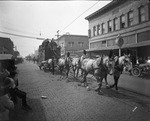 Team of six horses pulling a circus wagon that leads a circus parade down a brick-laid street in Breckenridge, Texas by Basil Clemons 1887-1964