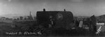 Family prepares breakfast beside their truck which is parked next to an oil tank near the small town of Stanton, Texas (in background) by Basil Clemons 1887-1964